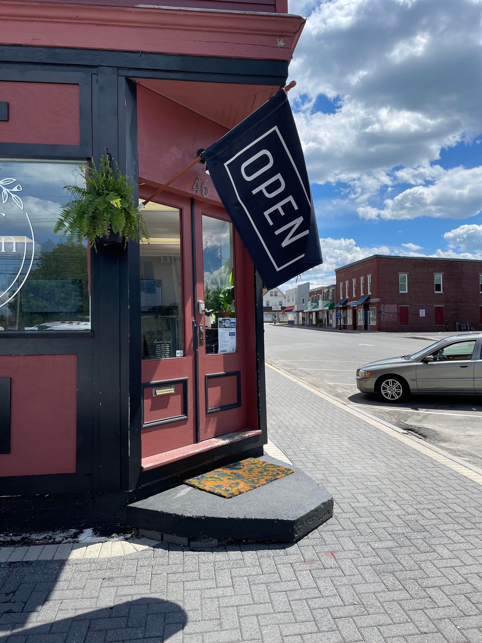 Brewer Nutrition’s deep-maroon corner storefront on Center Street, with an OPEN flag by the door